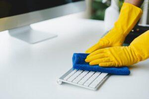 Die Reinigungskräfte verwenden Tücher und sprühen Desinfektionsmittel. Wischen Sie den Schreibtisch und den Boden im Büroraum.