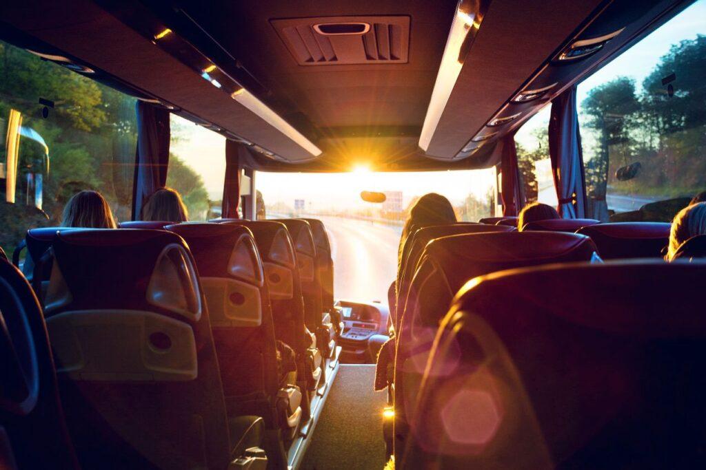 Klassenfahrt Berlin – Schuelergruppe sitzt im Reisebus bei Sonnenaufgang auf dem Weg zum Ziel