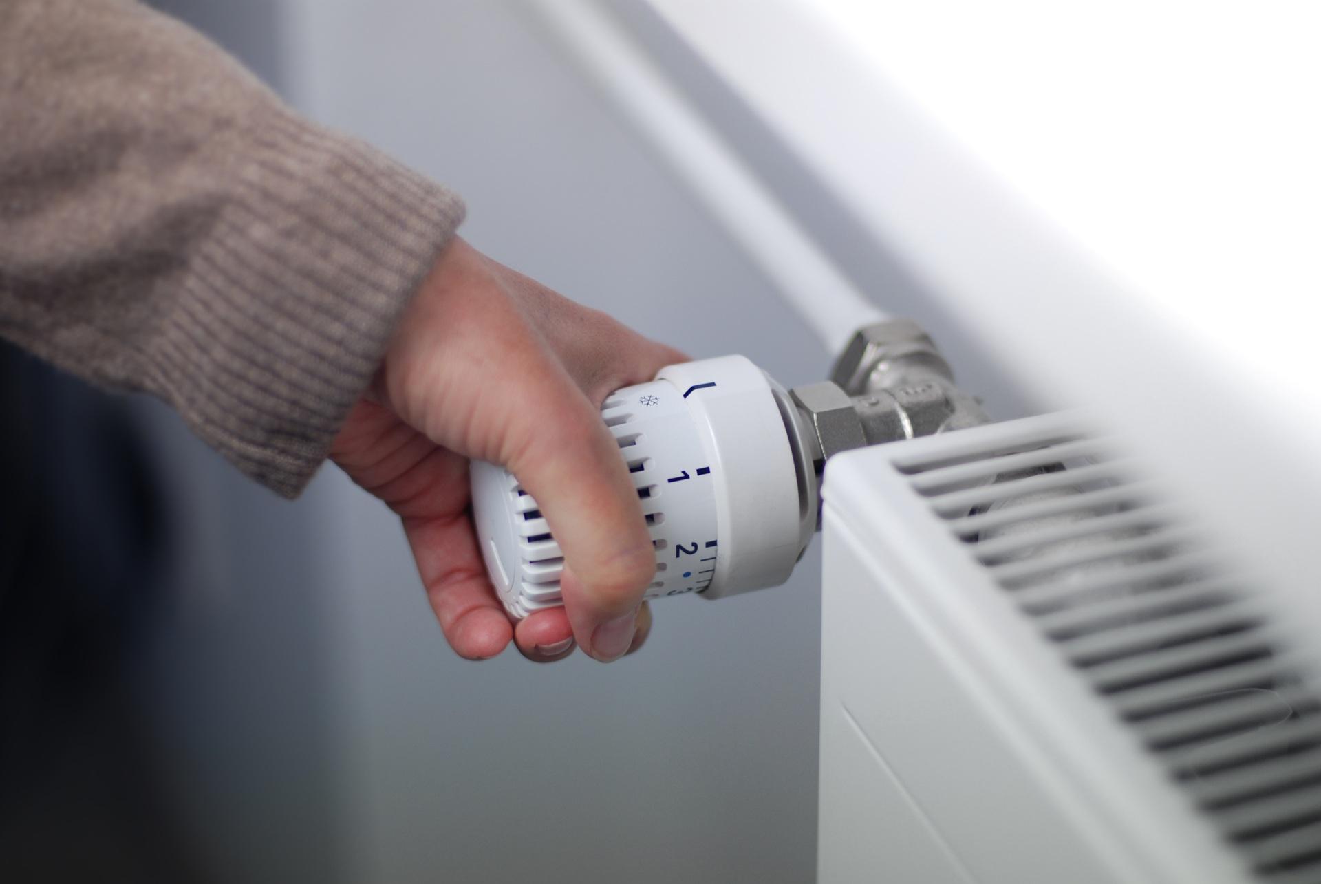 Hand dreht Heizungsregler für Energieeinsparung | Abwassertank